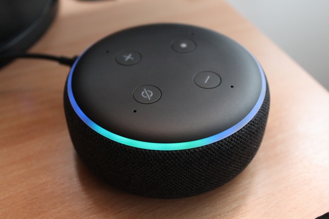 An Amazon Alexa voice assistant on a table. It is a round speaker with some buttons.
